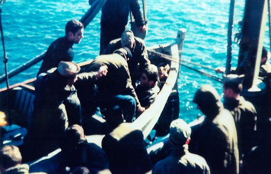 Lou Ives being helped out of whaleboat by USS Hailey crew.