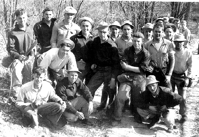 “Motley Crew” in the Boondocks  USNPFS Ottumwa, Iowa.”      survival training         front row (kneeling-bent over), left to right:    	Richard Green, Harry Franklin (?), Bob “Sport” Horton,   	Coleman Goatley    standing, left to right:    George Waters, Vern Yates, Gus Kinnear, Hal Marr, Bob Hamilton, Richard Jacinski, Jim May, Al Lewis, Gene Sizemore (?), Bob Iverson, Gordon Mayer (?), R. J. Woods      spring 1947