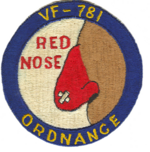 Patch with blue border and text VF-781 and ORDNANCE. Center shows a red nose with a bandage, with RED NOSE above it. Background is cream-colored.